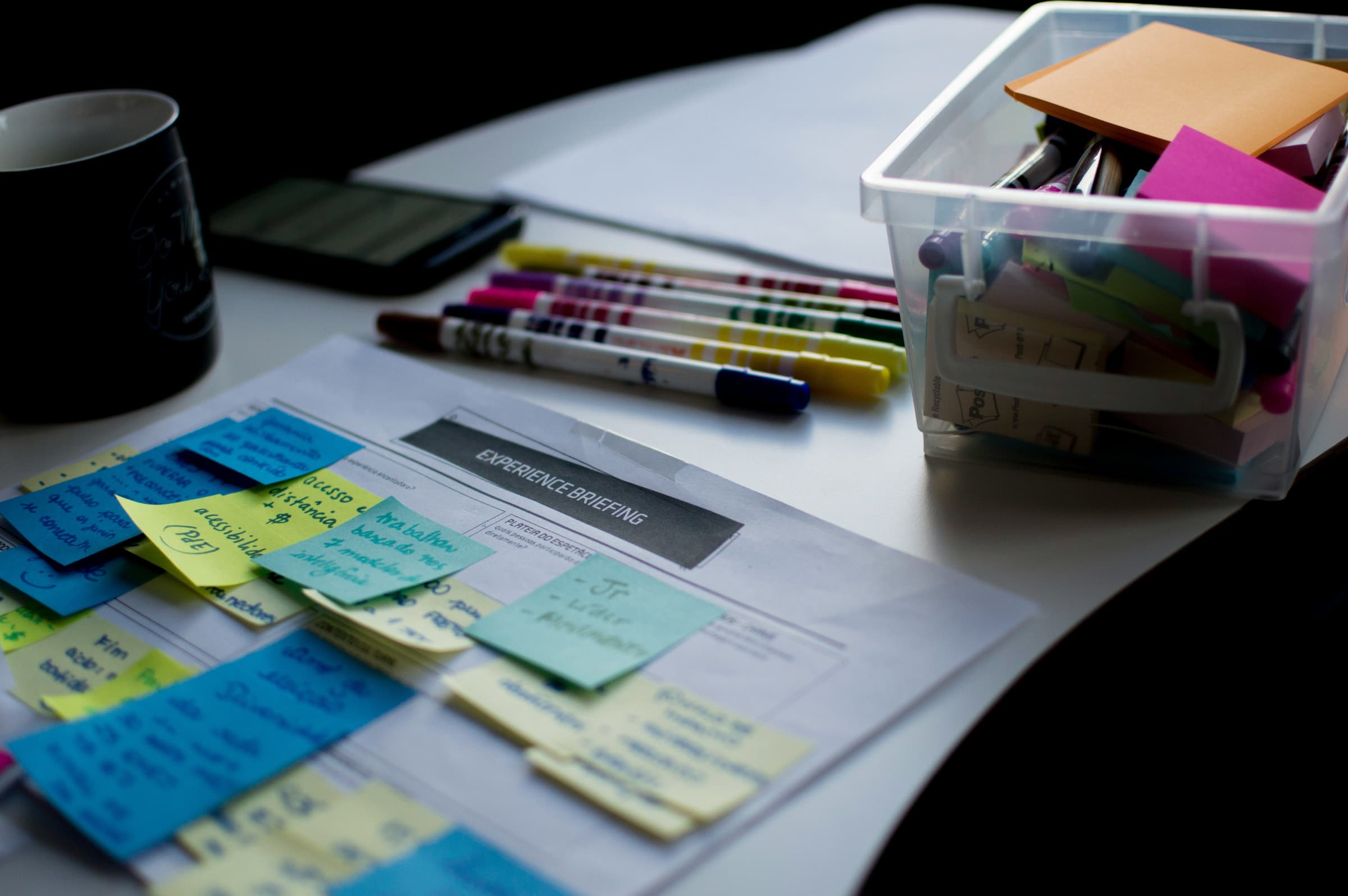 Sticky notes on a printed document beside pens
